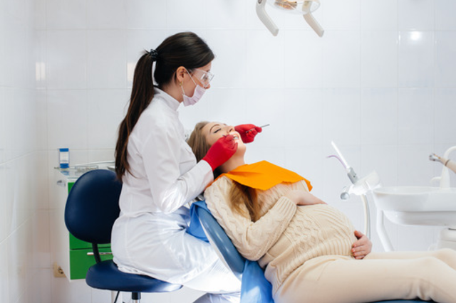 A pregnant woman receives dental care from dentist, highlighting safe practices.