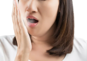A woman gasps, hand over her mouth, worried about her bad breath.